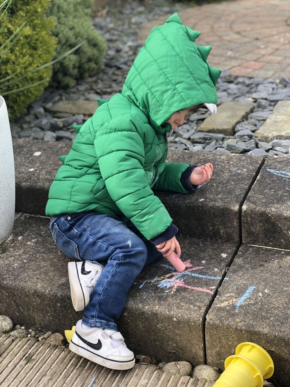 Max playing with sidewalk chalk in the garden