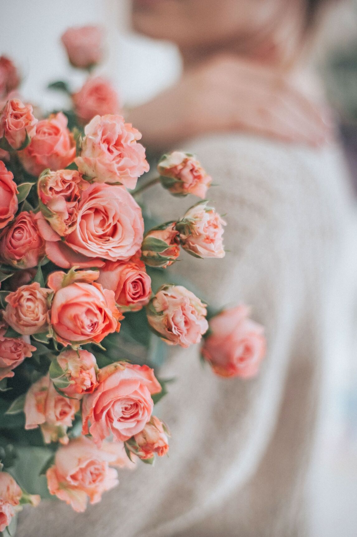woman carrying a bunch of pink roses